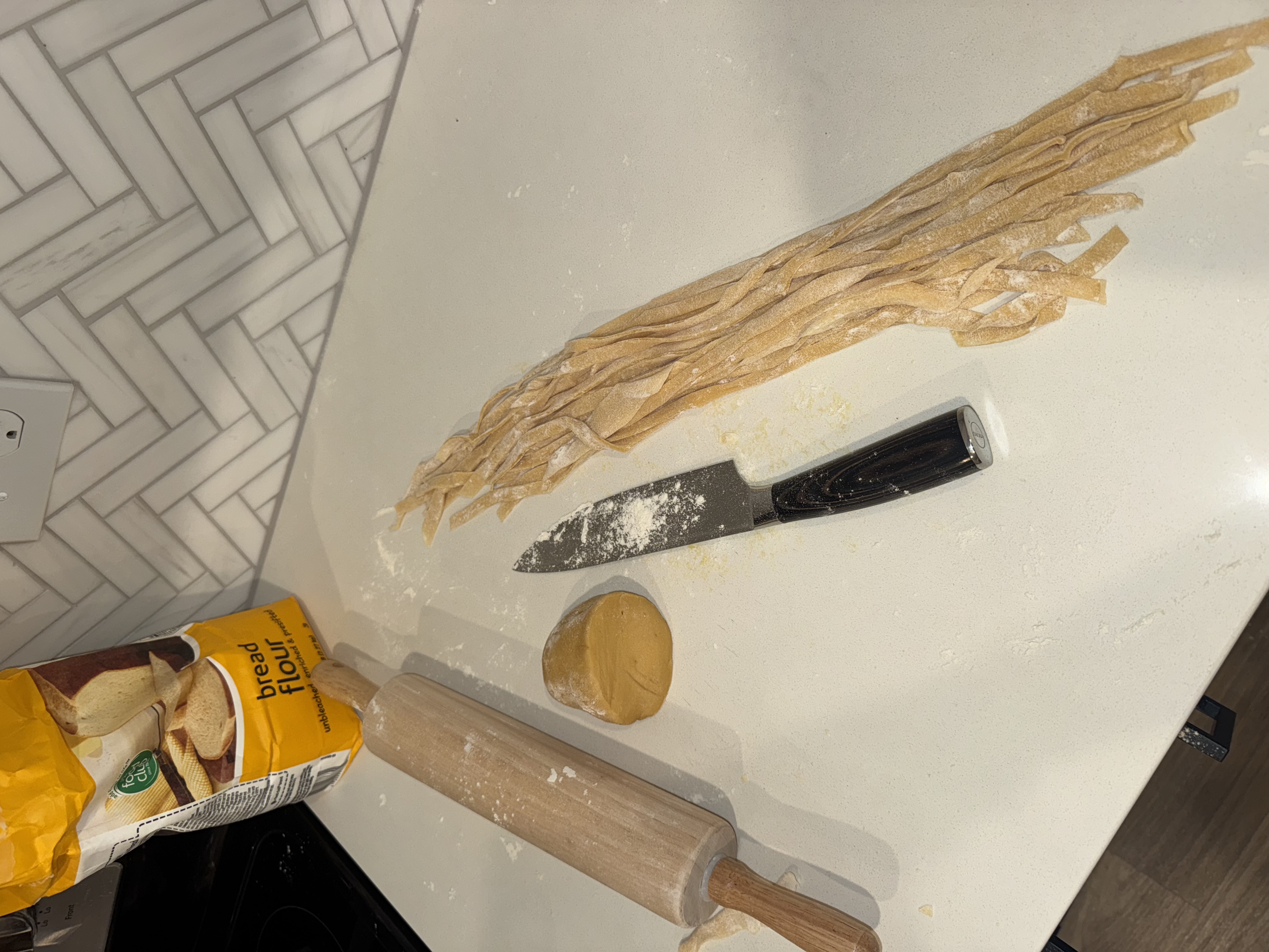 Fresh pasta noodles being made with flour and rolling pin
