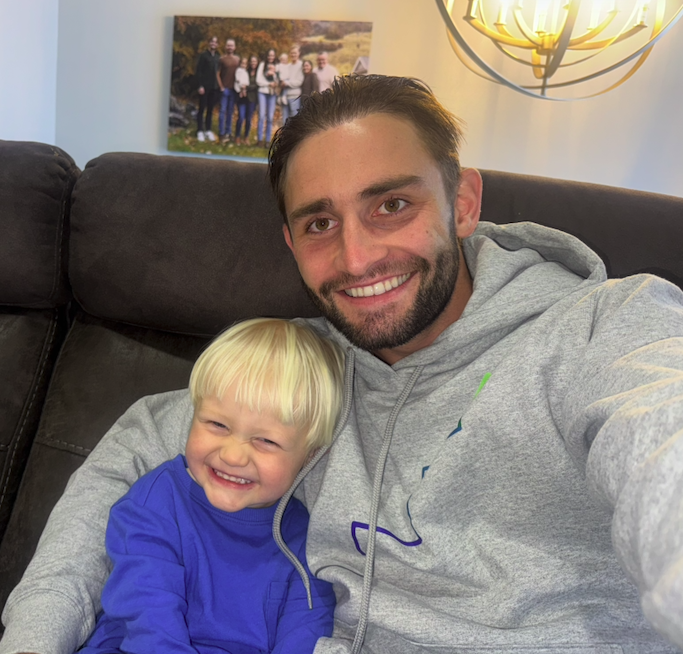 Zach with a young child, both smiling on a couch